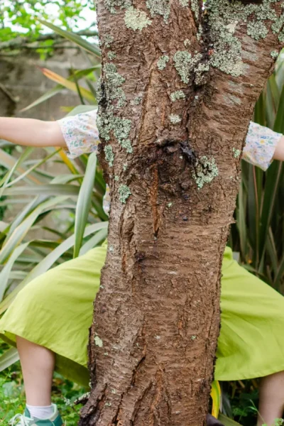 kiara porte la jupe-culotte Alchémille et le chemisier Bleuet. elle est cachée derrière un arbre